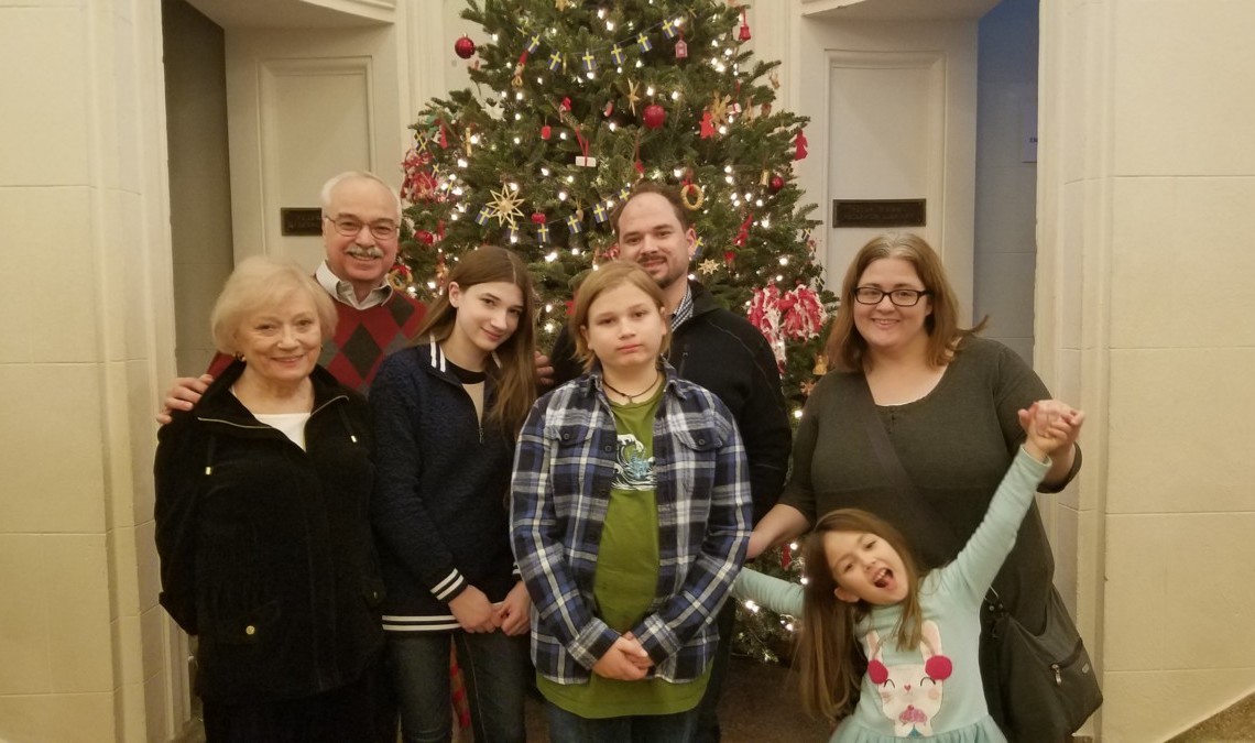 A family on the 19th floor posing in front of a christmas tree.