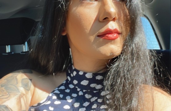 A woman with tattoos sitting in the back seat of a car on the 18th floor.