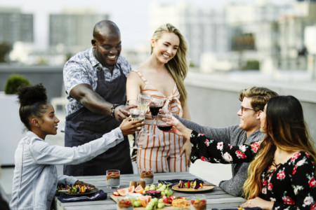 A group of people toasting wine on a rooftop at an End of Summer BBQ.